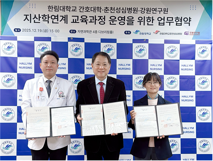 현수막 내용 : 한림대학교 간호대학 / 춘천성심병원 / 강원연구원 지산학연계 교육과정 운영을 위한 업무협약 일시 2025년 12월 19일 금요일 오후 3시 장소 자연과학관 4층 디브리핑룸1 주최 한림대학교 / 한림대학교 춘천성심병원 / 강원연구원 현수막 아래 3명의 대표가 서명된 업무 협약서를 들고 서있다.